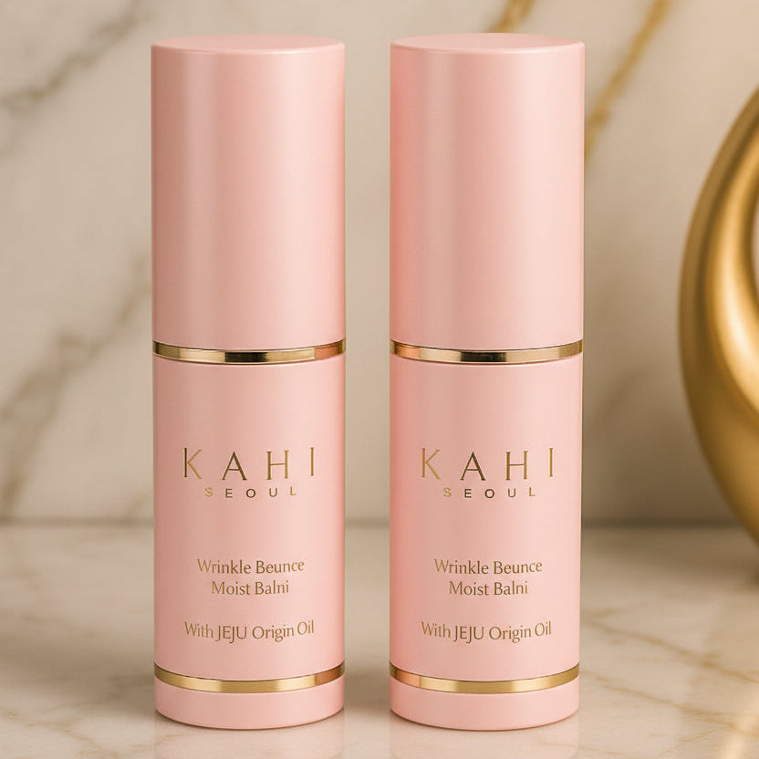 Two pink skincare bottles with gold accents on a marble surface.